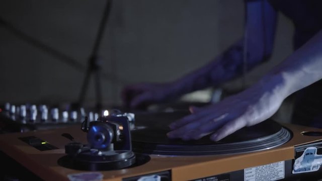 Disc jockey scratch vinyl record with music on turntable records player. Turntables vinyl disc in focus. Play music on dj audio equipment in night club. Close up,focus on djs hand on disc. Turntables