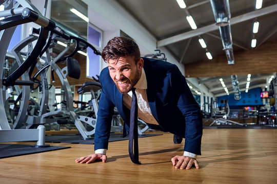 Businessman doing push-ups from the floor in the gym.