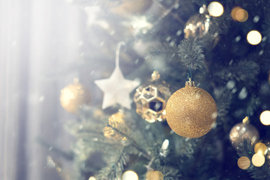 Closeup Of Gold Bauble Hanging From A Decorated Christmas Tree With Bokeh, Copy Space, Xmas Holiday Background.