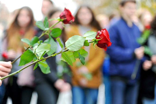 Jugendliche mit roten Rosen bei einer Gedenkfeier