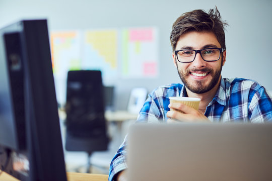 Portrait Of A Smiling Young Designer Enjoying Coffee While Taking A Break From Work