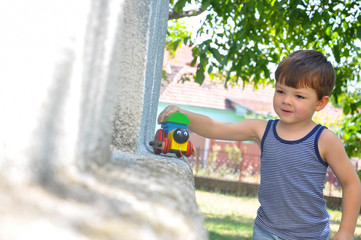 Child play with train toy outside. Play with wooden train in the yard