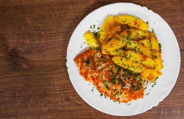 Grilled chicken breast with potato in a plate on a wooden background. with copy space. top view