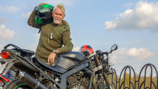 Portrait of a cheerful older man with a motorcycle