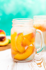 Homemade iced lemonade with ripe peaches. Fresh peach ice tea in a mason jar.