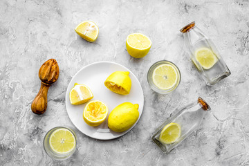 Fresh homemade lemonade. Lemons, juicer, glass for beverage on grey stone background top view