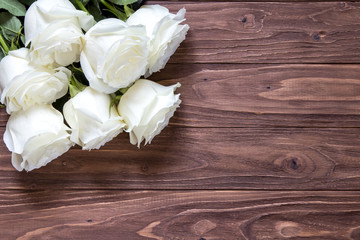 Macro view of beautiful white roses bouquet on the corner of the wooden table. Romantic wallpaper for beloved couples