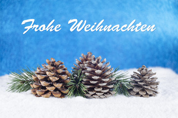 Group of pine trees and some branches with text in German "Frohe Weihnachten" on a white snow and blue background