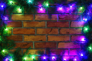 Wreath and garlands of colored light bulbs.Christmas background with lights and free text space. Christmas lights border. Glowing colorful Christmas lights on a brick wall background. New Year.  