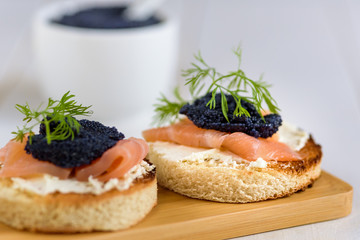 Appetizer toast bread with cream cheese, smoked salmon and black caviar decorated by dill.