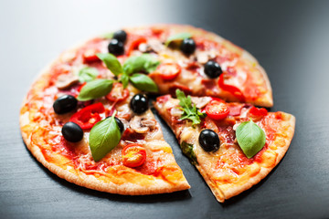 Mozarella Pizza slices with  melting cheese and olives served at a pizzeria or restaurant on black board with copy space