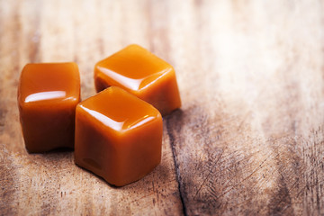 Homemade salted caramel pieces  on wooden  background. Golden Butterscotch toffee candy caramels...