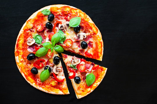 Mozarella Pizza slices with  melting cheese and olives served at a pizzeria or restaurant on black board with copy space