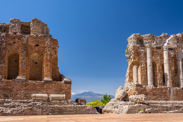 Fototapeta na wymiar Ruins and columns of antique greek theater in Taormina and Etna Mount in the background. Sicily, Italy, Europe.