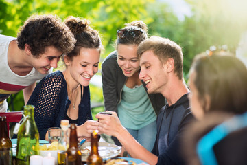 a young man shows his friends the pictures he took on his phone