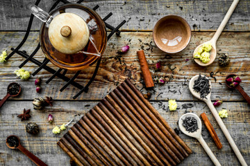Tea party set. Tea pot, cups, dried tea leaves, fllowers, spices on wooden background top view