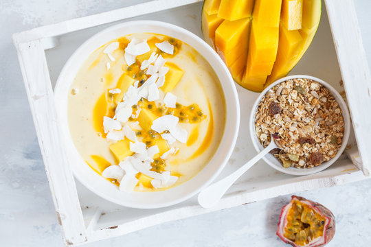 Mango smoothie bowl with coconut, granola and passion fruit.