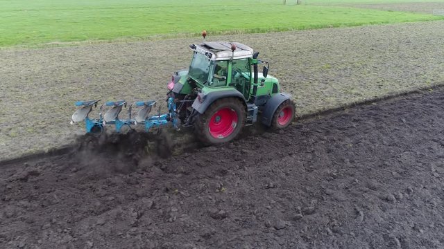 Aerial view footage of tractor plowing land for initial cultivation of soil in preparation for sowing seed or planting to loosen or turn the soil stable footage on right side of agricultural machine