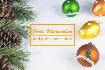 Group of pine trees, some branches and colorful baubles and Christmas balls with text in German "Frohe Weihnachten und gutes neues Jahr" in white snow background