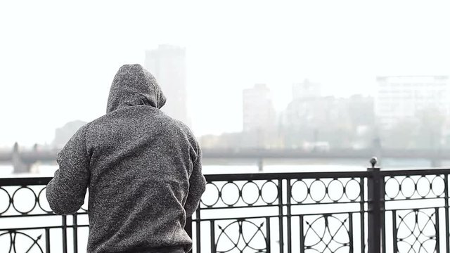 A fighter training on a bridge in the fog. Boxer trains technique of strikes in a foggy day in the center of the city