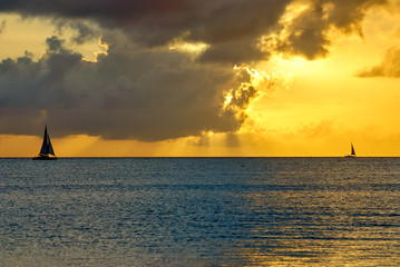Fototapeta na wymiar Silhouette of sailboats at sea with golden ocean sunset 
