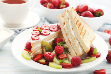 Toasts bread with various berries on white wooden table