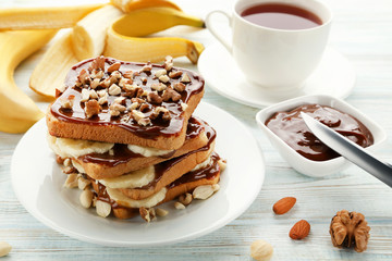 Toasts bread with bananas, walnuts and chocolate on white wooden table
