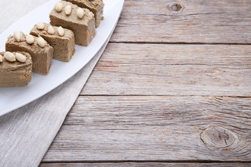 Tasty slices of halva in white plate on grey wooden table