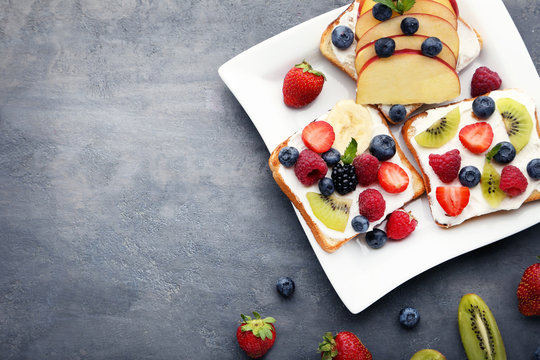 Toasts bread with berries in plate on grey wooden table