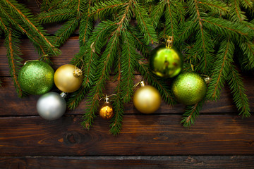 New Year's greens, yellow and silver balls with live fir branches on a wooden background. Top view