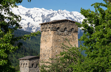Fototapeta premium Ancient stone tower against the background of snow-capped mountains. Selective focus.