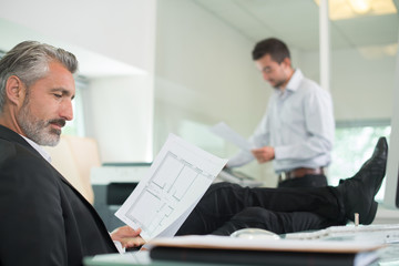 Senior businessman with feet up on desk