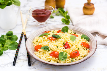 Noodles with pepper, lettuce leaves and sesame seeds in a ceramic plate