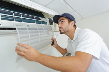 portrait of mid-adult male technician repairing air conditioner