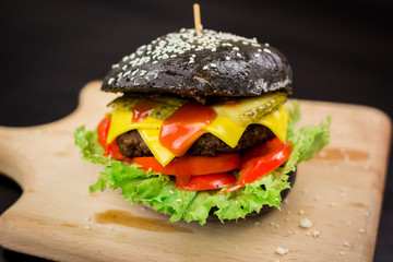 Black hamburger with cheese and cucumber