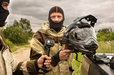 Close up of Two men outdoors wearing balaclava helmets and motorcycle uniforms.
