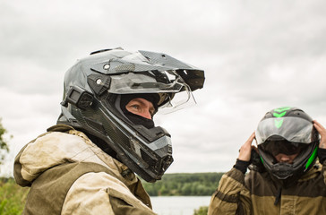Two men outdoors wearing motorcycle helmets and uniforms.