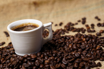 Cup of coffee on sackcloth with coffee beans
