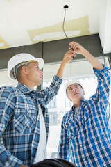 male electrician fixing light on ceiling