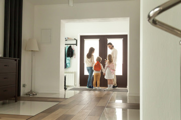 Happy family going out standing in hallway opening door, parents leaving home with kids holding son and daughter hands, mother father taking children to school, spending weekend together, rear view