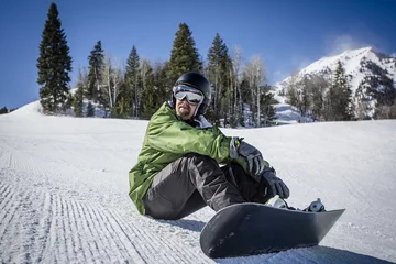 Fotobehang Wintersport Male adult snowboarder enjoying a day at a ski resort while rest on a perfectly groomed ski slope. A beautiful day on the slopes having fun  © Brocreative