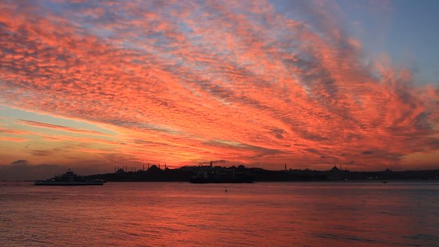 Setting sun fired up the sky and Bosphorus waters. 1 minute of HQ HD. Breathtaking view over shimmering waters of Istanbuls magnificent Bosphorus. Sunset at Sarayburnu over Blue Mosque and Hagia Sophi