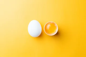 Zelfklevend Fotobehang White egg and egg yolk on the yellow background. topview © masanyanka