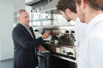 Naklejka na ściany i meble Manager teaching waiters how to use coffee machine