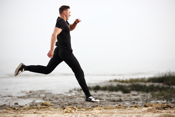 Fototapeta premium Athletic man running by the rocky seaside coast.