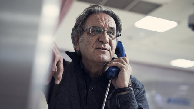 Senior man talking on public payphone