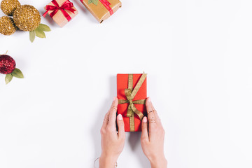 Red gift box with a golden bow in female hands