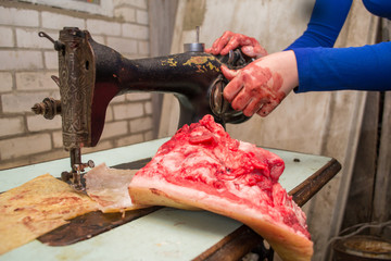 a woman sews from bloody skin and meat on an old retro sewing machine. Animal protection