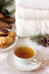 Winter composition with tea and biscuits in the background of a rug or pullover, cones and fir branches.