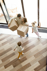 Family and children moving into new home, kids playing running around parents holding boxes...